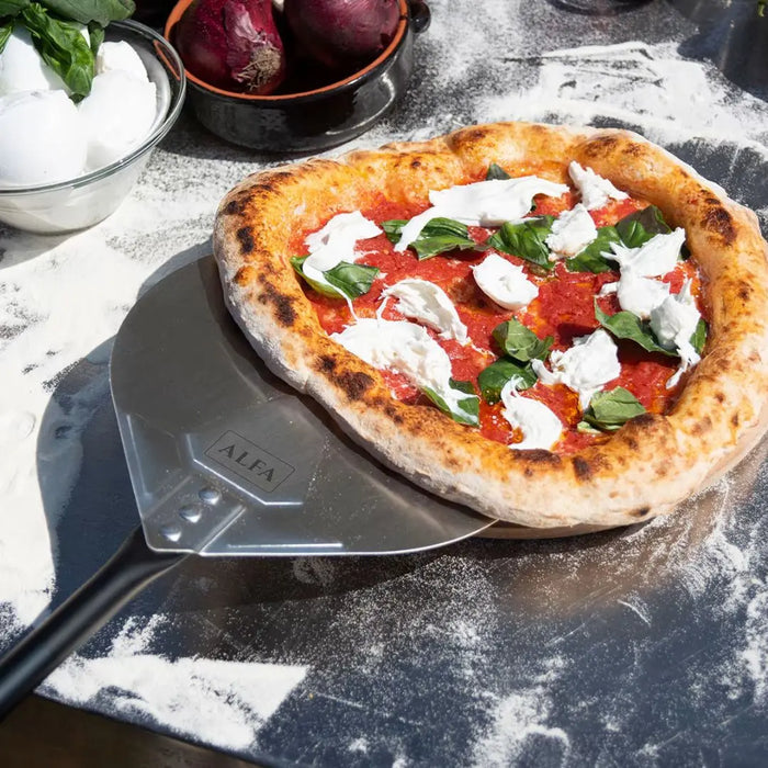 Pizza with basil and cheese on a stone surface with Alfa Pizza Turning Peel