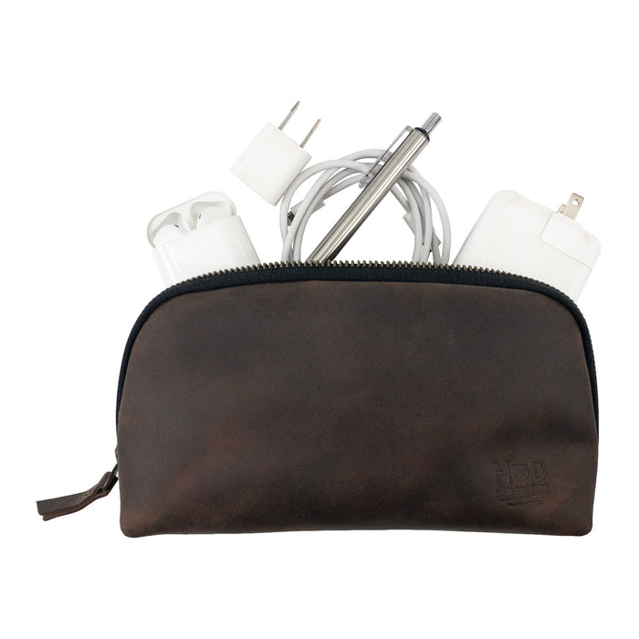 Hide & Drink's Small Tech Organizer filled with chargers and cables. This small tech bag offers a rustic look while being practical for everyday use. It's made from durable full grain leather, highlighting artisan techniques handmade in La Antigua Guatemala & Oaxaca Mexico.
