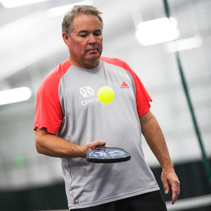 Man holding a paddle and a ball, likely in an indoor sports facility