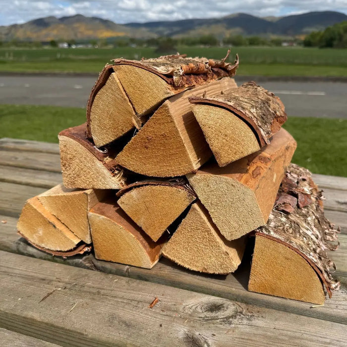 Stack of chopped birch kiln dried cooking logs for pizza oven on bench table