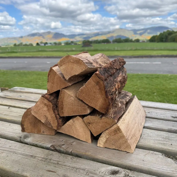 Stack of oak kiln dried cooking logs for pizza oven on bench